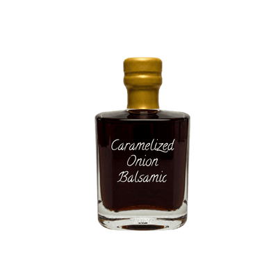 A small clear glass bottle filled with very dark brown balsamic, sealed with a gold cap, and labeled 'Caramelized Onion Balsamic' in white script, centered on a plain white background.