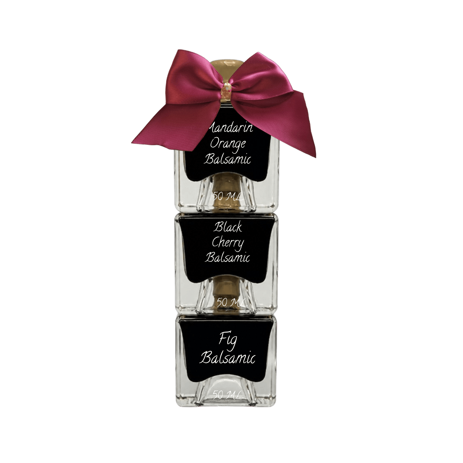 Three stacked clear glass bottles of scented hair oil with black labels reading 'Amandarin Orange Balsamic,' 'Black Cherry Balsamic,' and 'Fig Balsamic,' tied together with a large magenta satin bow on a white background.