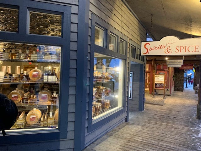 Storefront with 'Spirits & Spice' sign and display of bottles and items.