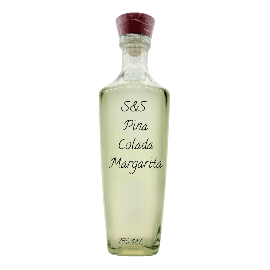 A clear glass bottle of S&S Pina Colada Margarita with a dark red cork stopper, containing a pale yellow liquid, set against a plain white background.