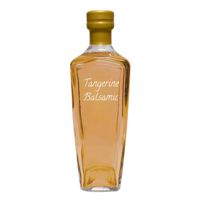 A clear glass bottle of Tangerine Balsamic with amber-colored liquid, a gold cap, and white script text on the front, isolated on a white background.
