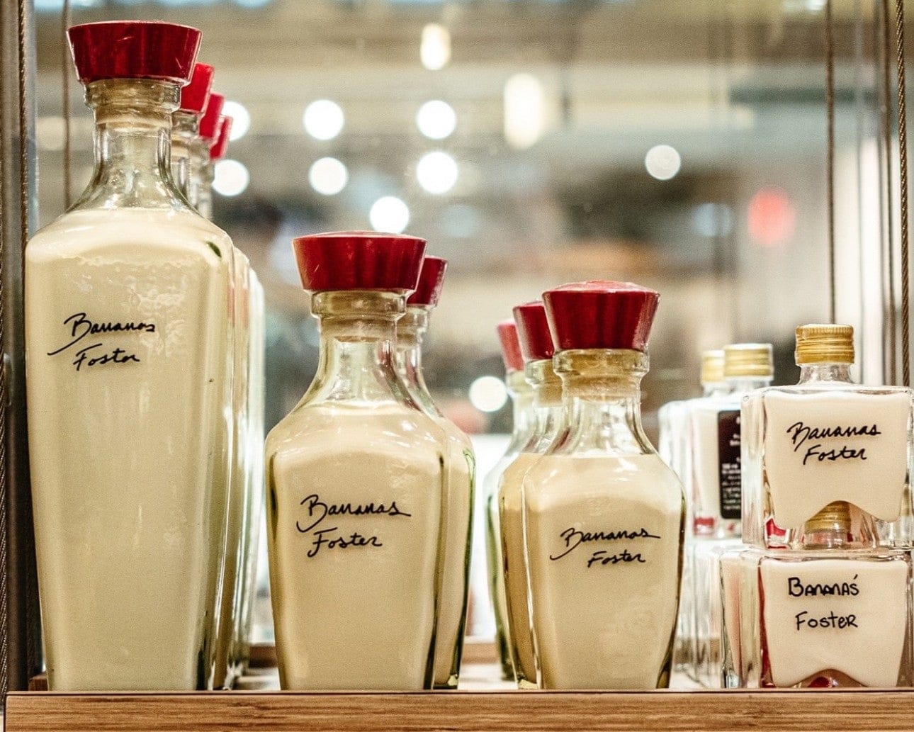 Bottles of Banana Foster sauce on a shelf with a tattoo parlor sign in the background.