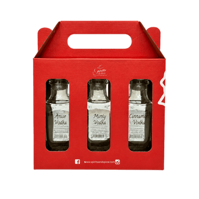 A red cardboard 3-pack carrier holding three small glass bottles of vodka: Anise Vodka, Minty Vodka, and Cinnamon Vodka. The carrier has a handle cutout and visible 'spiritsandspice' branding.