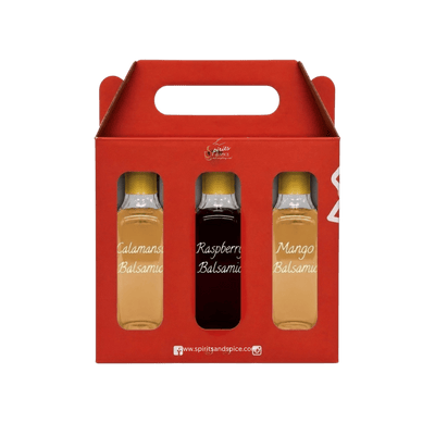 A red gift box containing three small bottles of fruit balsamoo syrup: Calamans Balsamoo, Raspberry Balsamoo, and Mango Balsamoo, shown on a plain white background.